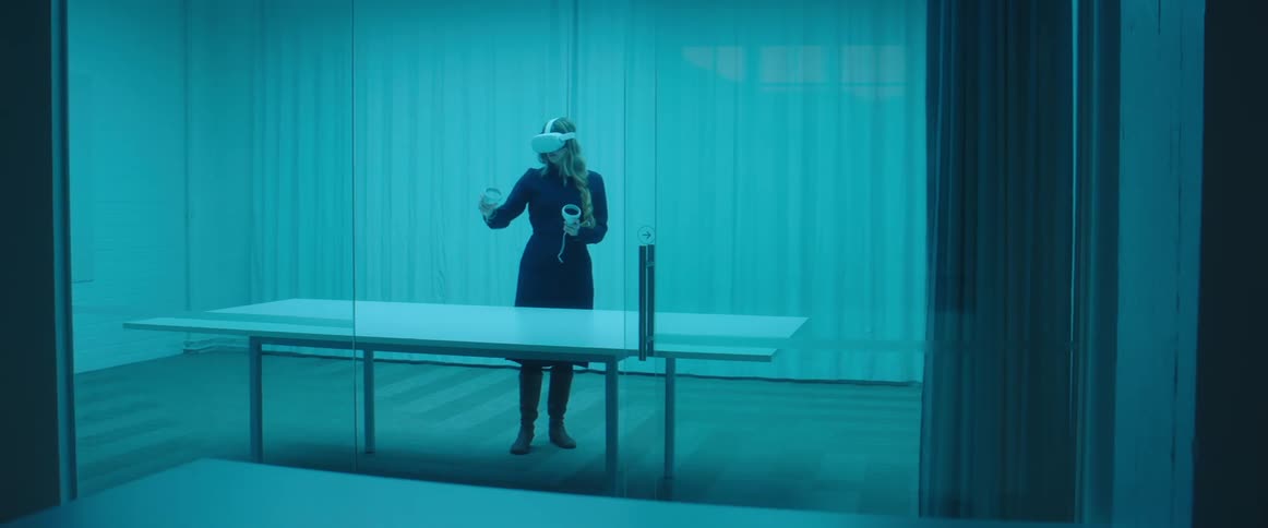 A woman is using a virtual reality headset in the large room