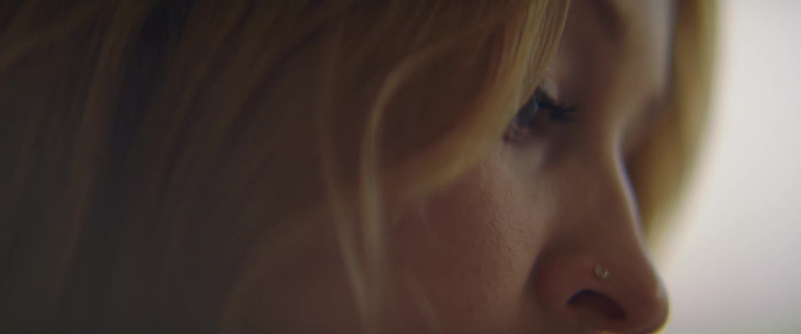 A woman with a nose ring in a room with a wall in the background
