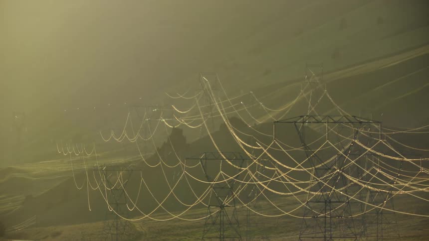 Massive electrical transmission lines carrying electricity across the USA in the sunset glow communicating energy needs in america and the world
