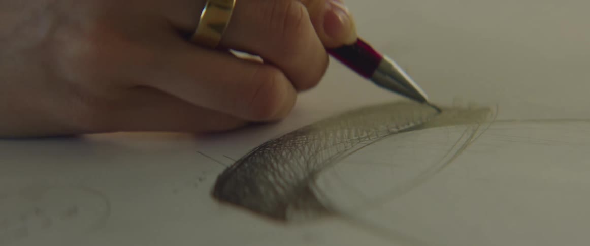 A hand sketching a drawing on a piece of white paper