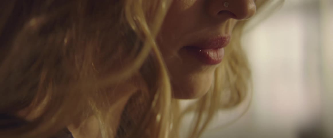 A blode female with long hair in a room that is showing a closeup of her head and face