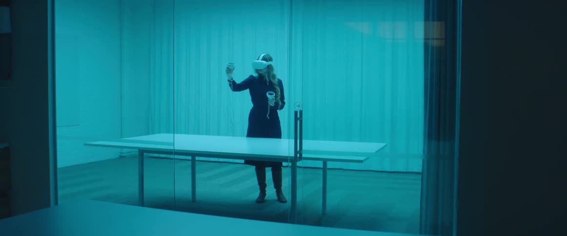 Woman testing virtual reality goggles and controls inside an office
