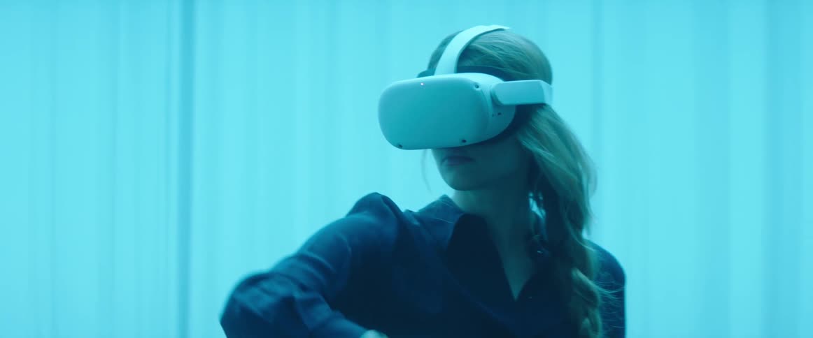 Blonde woman wearing vr headset moves controller around near curtains