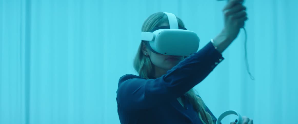 Woman testing virtual reality goggles and controls inside an office