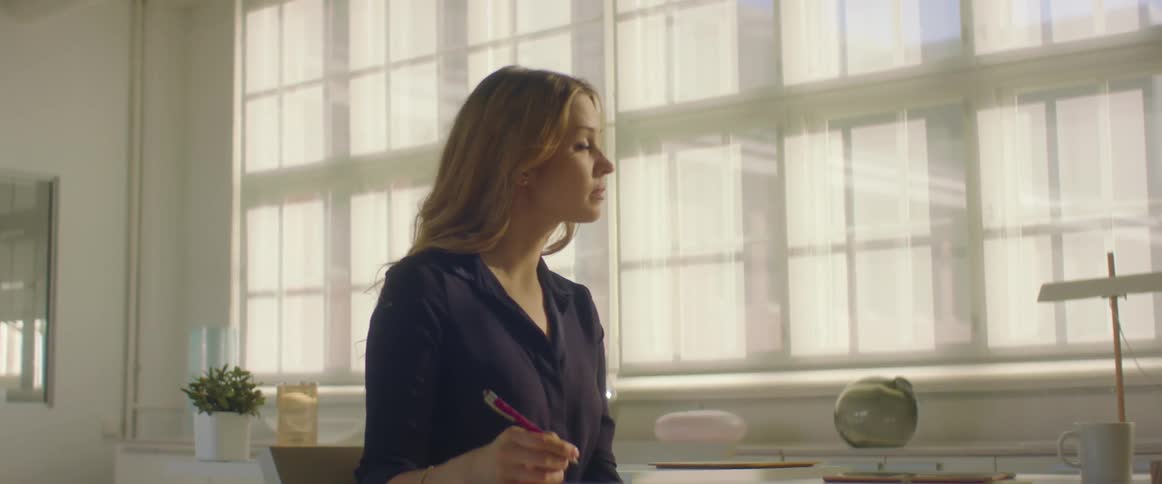 Woman holding a pen sitting at a desk in the office
