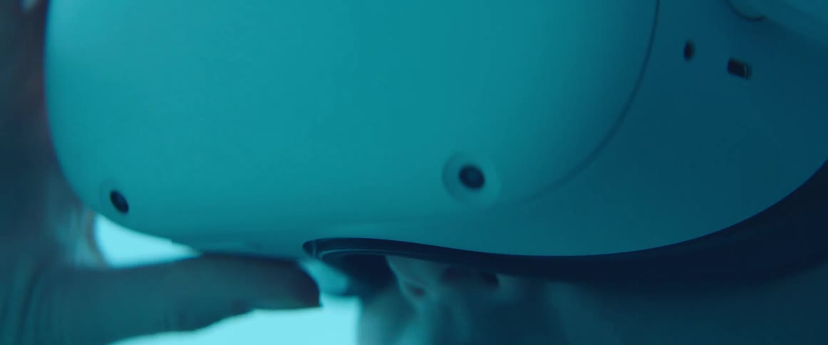 A woman places a virtual reality headset on her head while indoors