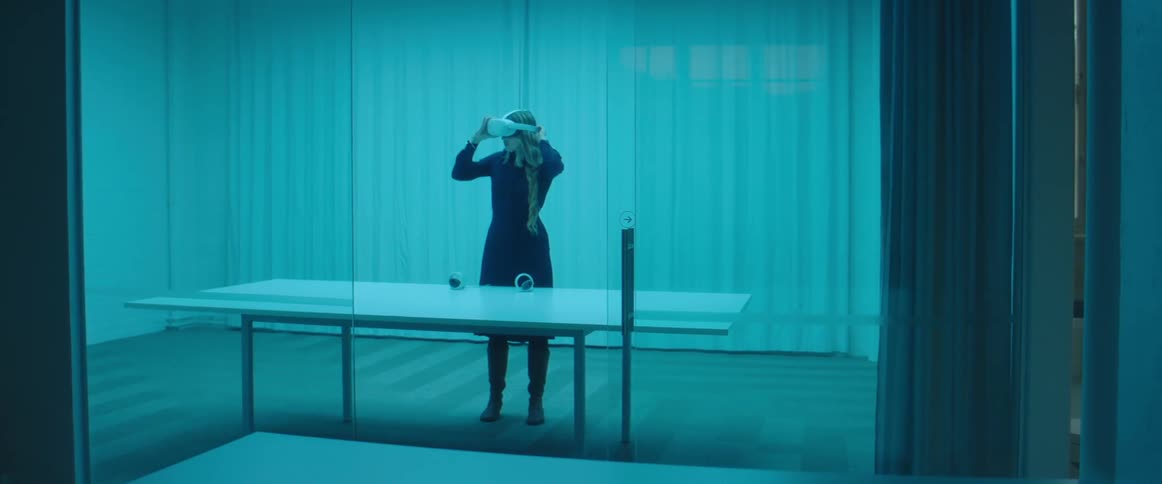 A woman walks into a large office room and picks up a virtual reality game