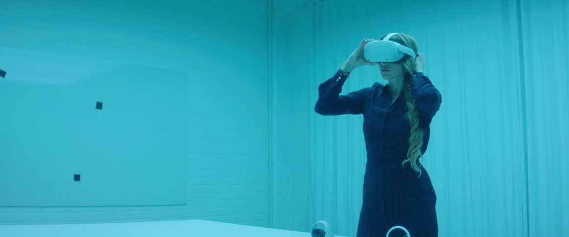Woman testing virtual reality goggles and controls inside an office