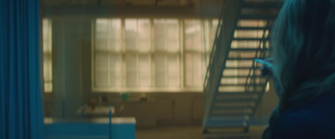 A woman in a room drawing with a stylus with a staircase and a window in the background
