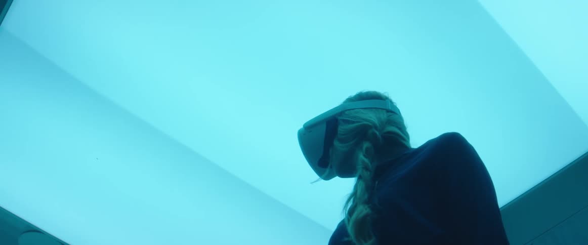 A woman in a room with a virtual reality headset with a wall in the background