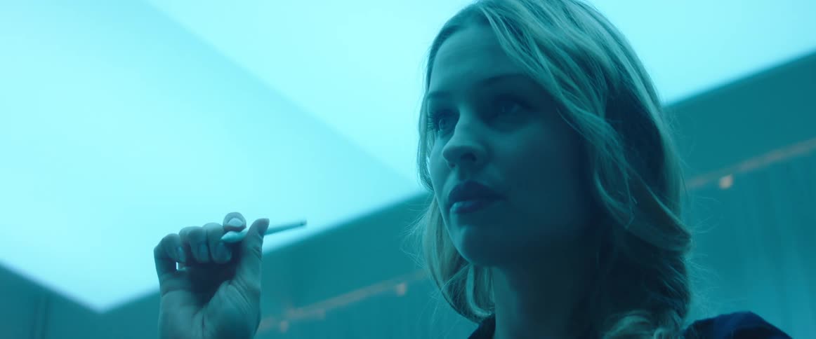 A woman in a room drawing with a stylus with a wall in the background