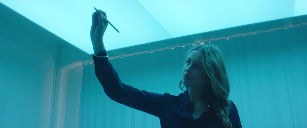 A woman in a room drawing with a stylus with a wall in the background