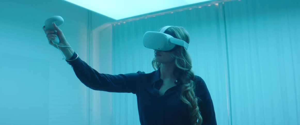 A woman in a room with a virtual reality headset and wires with a wall in the background