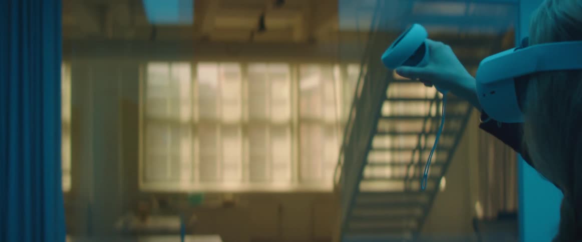 A woman in a room with a virtual reality headset on with a staircase and a window in the background