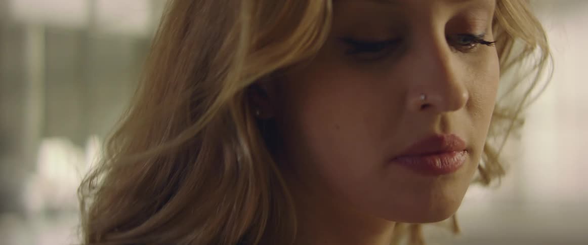 A woman with a nose ring in a room holding a pen with windows in the background