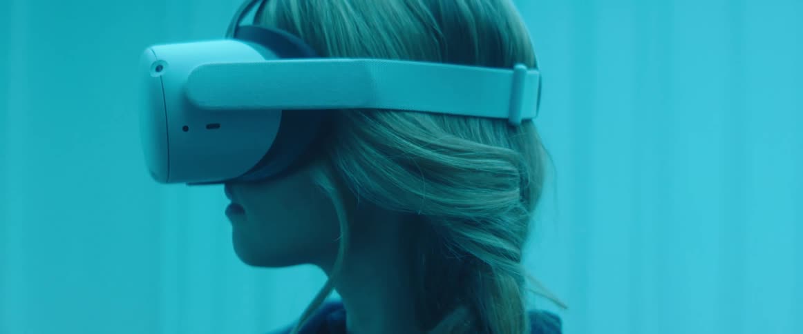 Woman testing virtual reality goggles and controls inside an office