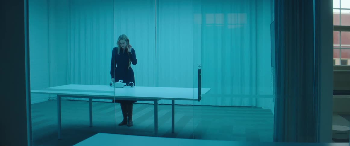 A woman walking into a room with a table and putting on a virtual reality headset