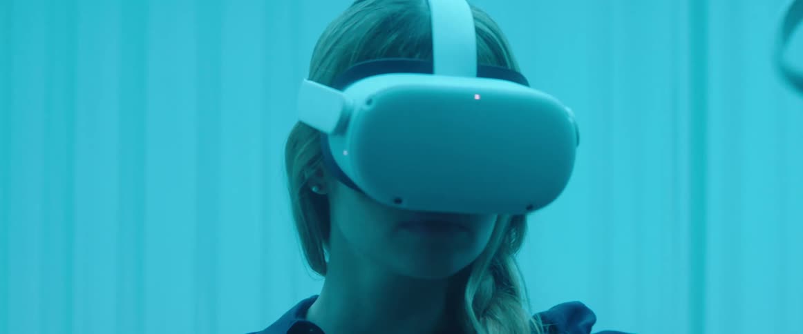 Woman testing virtual reality goggles and controls inside an office