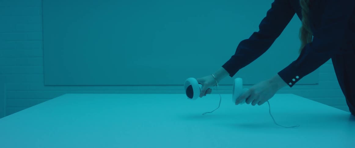 Woman testing virtual reality goggles and controls inside an office