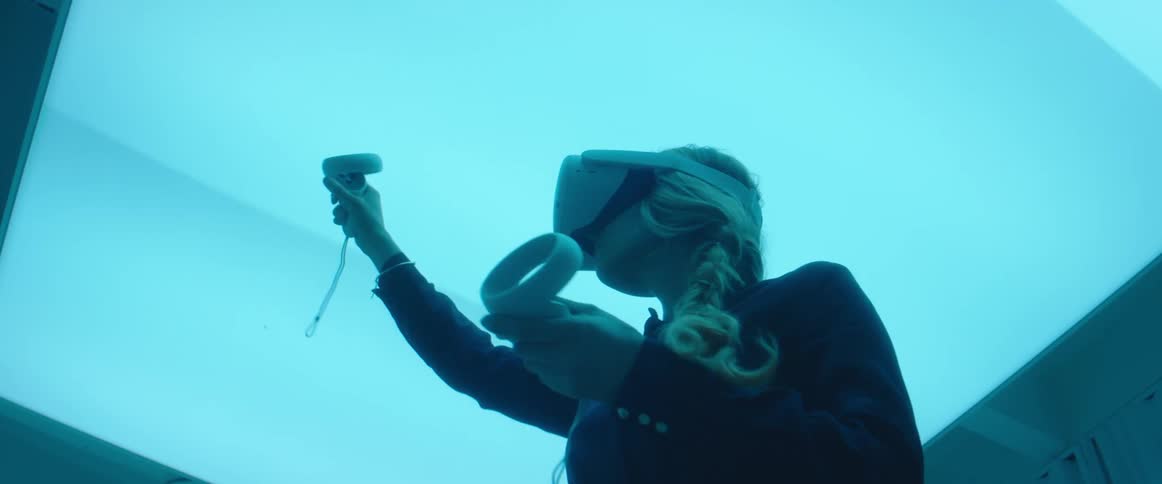 Woman testing virtual reality goggles and controls inside an office