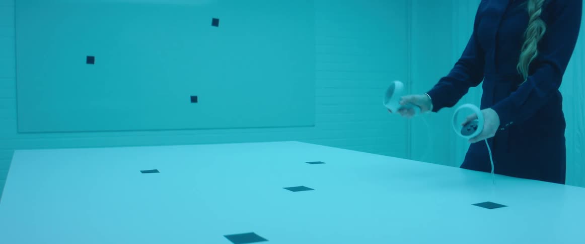 A woman moving two vr remotes around in the air in a room with blue lighting