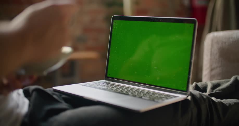 A person is sitting on a couch and looking at a laptop