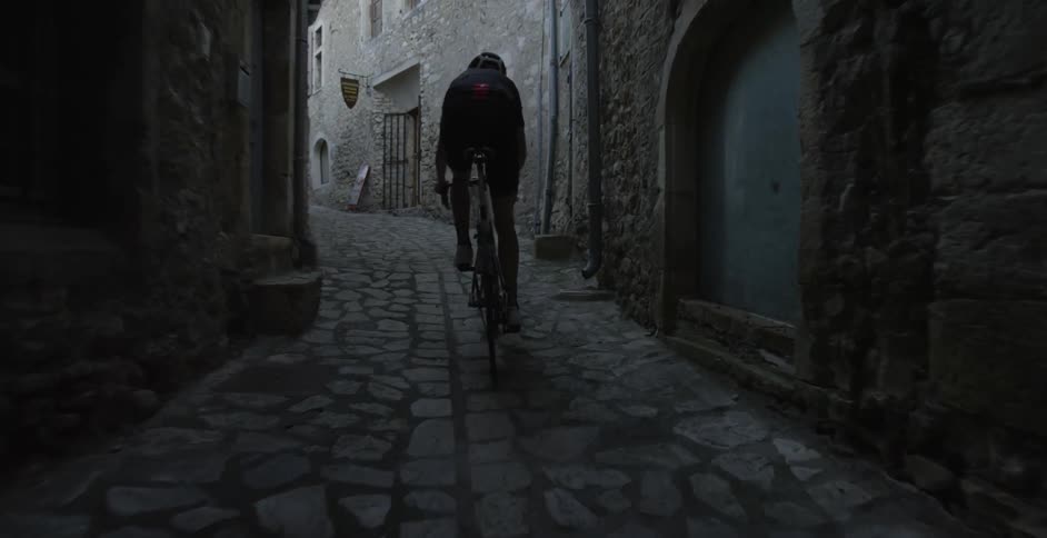A man rides a bike through alleys in a city