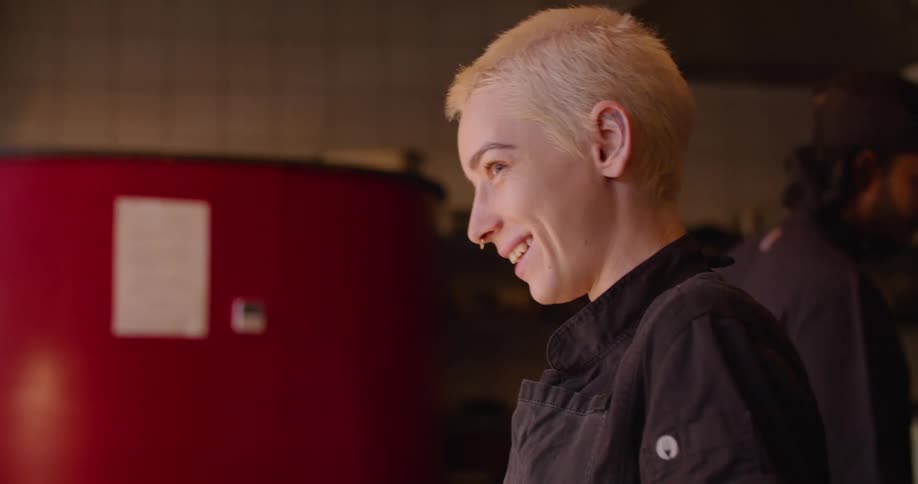 A young chef in a restaurant kitchen cuts vegetables