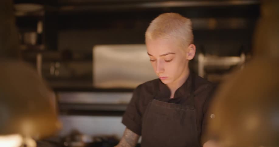 A woman with a apron cutting onions on a cutting board in a kitchen