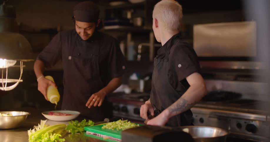 Two chefs work beside each other in a restaurant kitchen