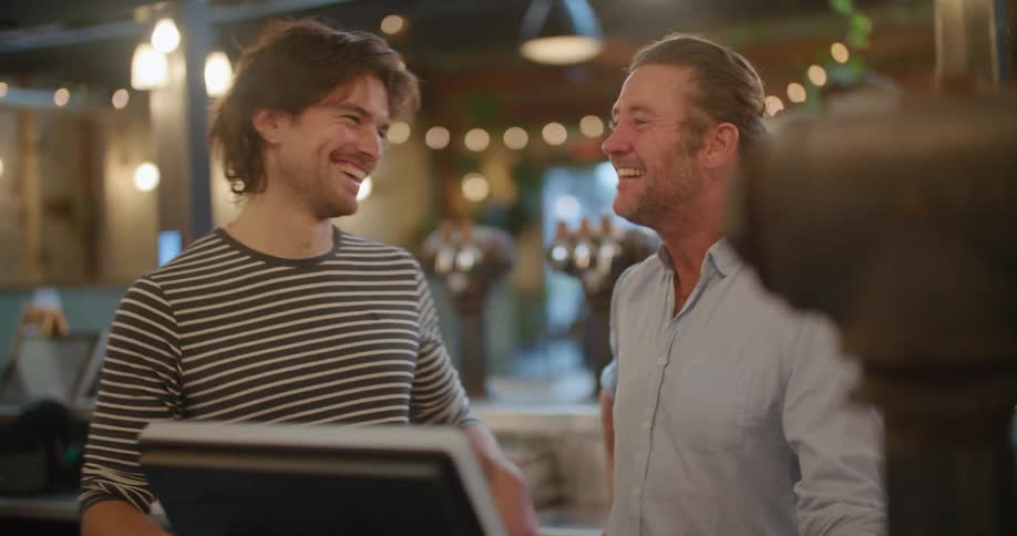 Two restaurant employees talk and laugh together standing outside