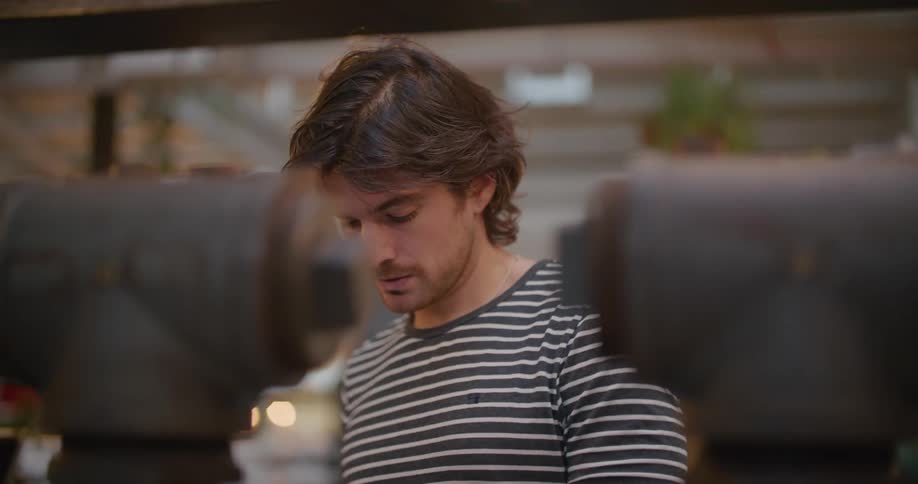 A man wiping a glass with a shelf in the background
