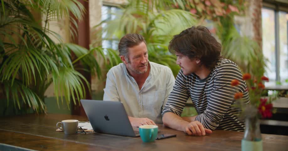 Two men working on a laptop on the table of a restaurant