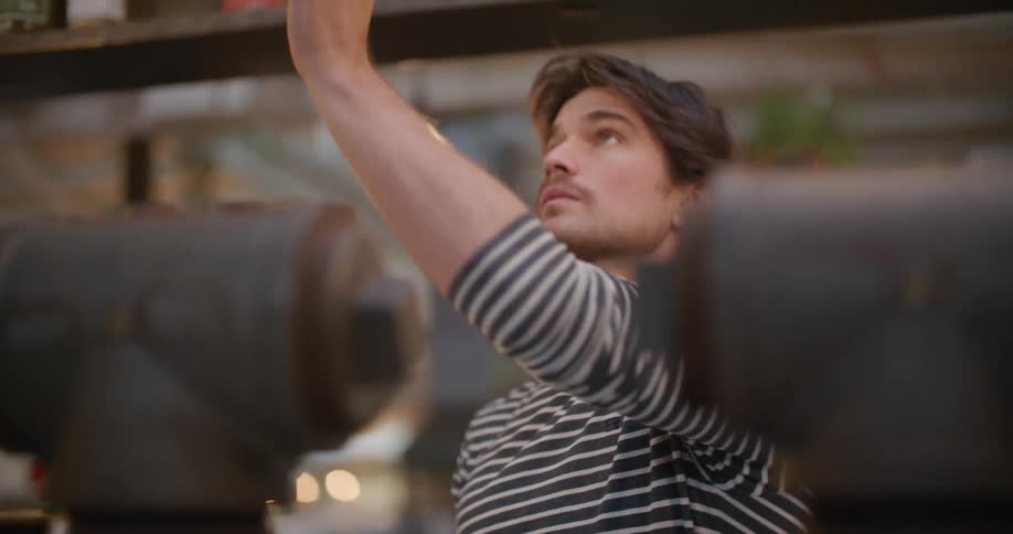 A male restaurant employee dries the inside of a glass and puts it away