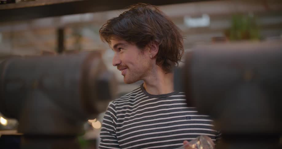 Waitress with a sweatshirt and long hair dries a glass with a piece of cloth in the cafeteria
