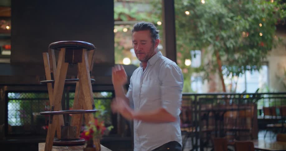 A male restaurant employee stacks bar stools on top of a counter outside