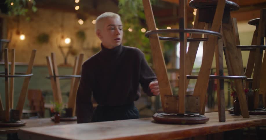An employee taking stools off of a table