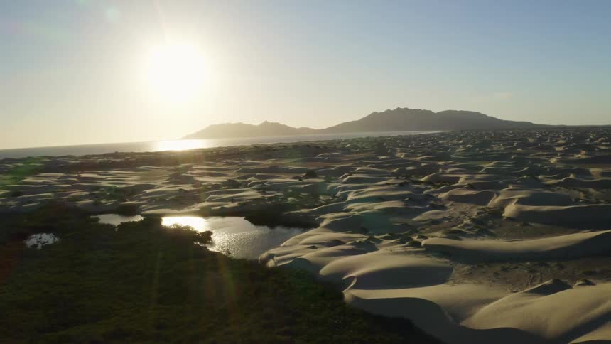 An aerial view of sandy hills in a desert on a bright day