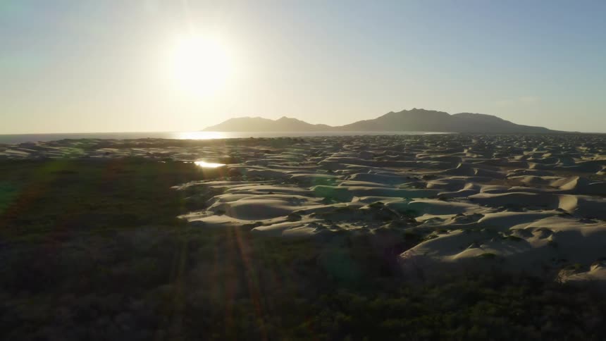 Desert with mountains on the horizon and a bright sun in the sky