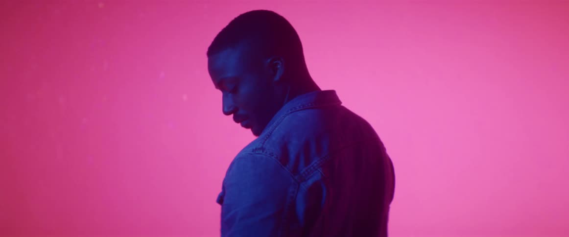 A man standing in front of a pink backdrop