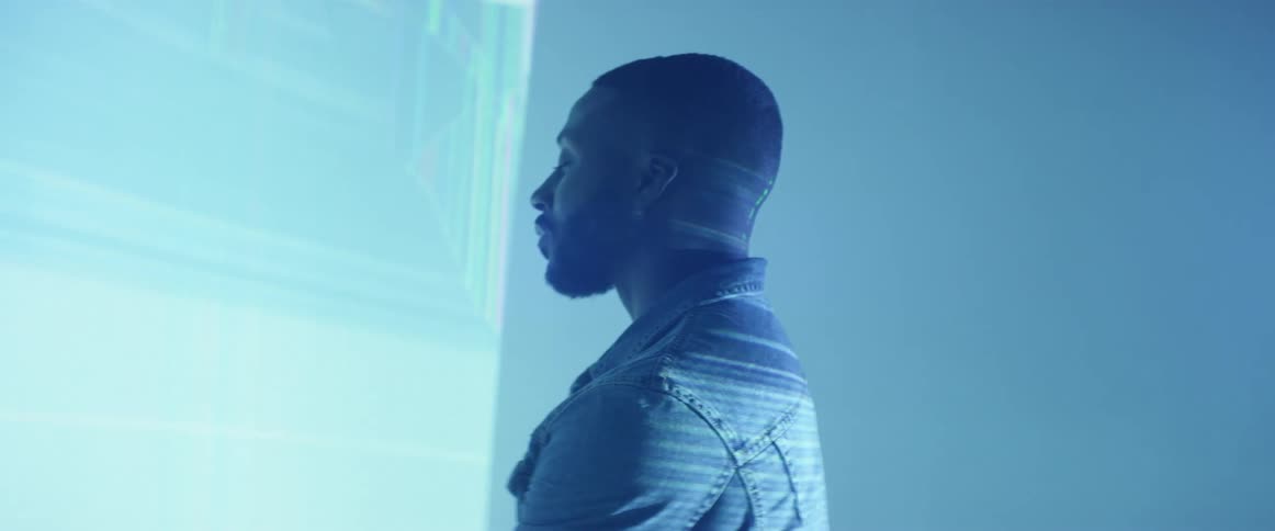 A man standing and staring at a digital screen inside of a room