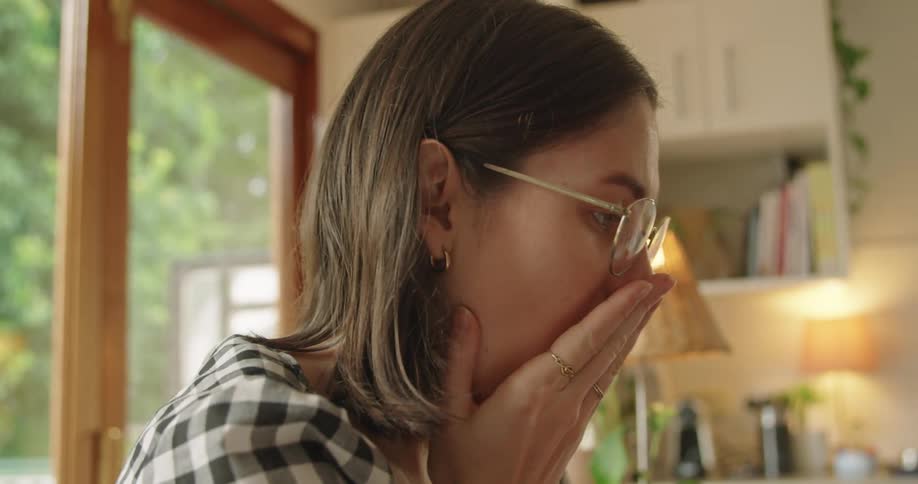 A woman sitting down at home yawns and smiles