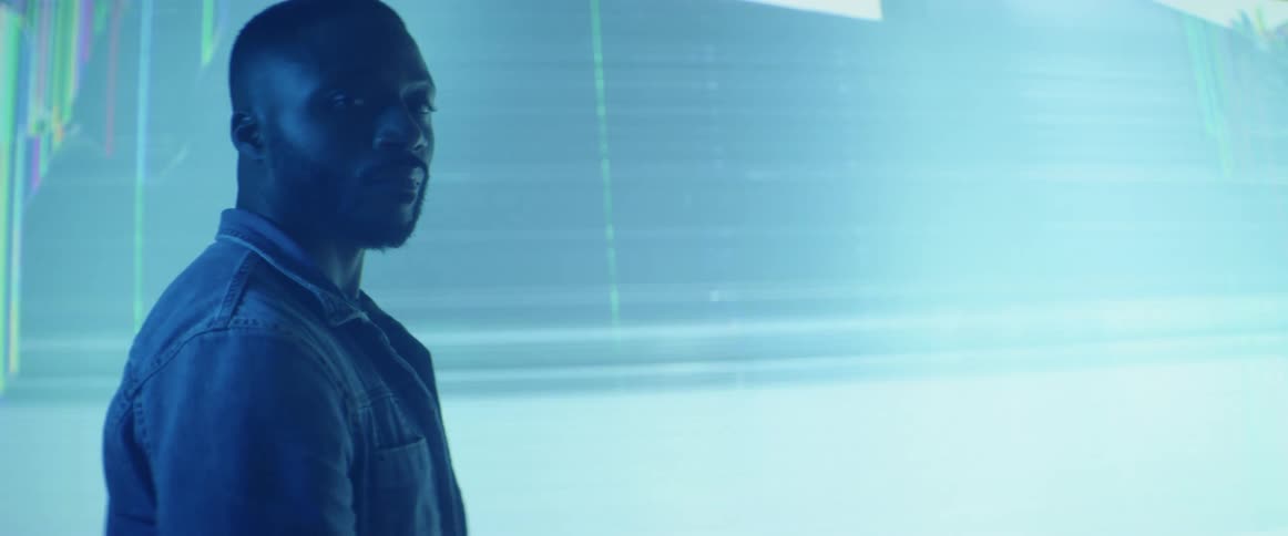 A man stands in front of a large screen with lines running across it