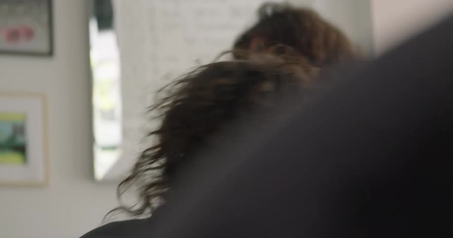 A woman smiles as a hairdresser tells her to move to another chair