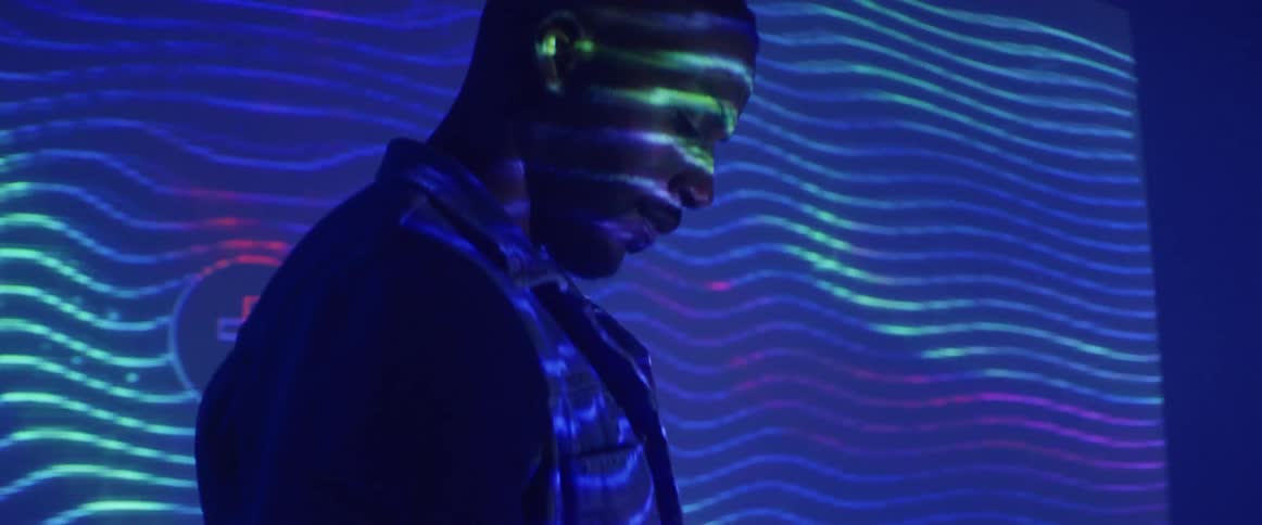 Man reading a book in front of a colorful video projected on a wall