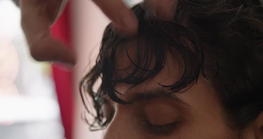 A man in a room getting his hair cut with scissors and a comb