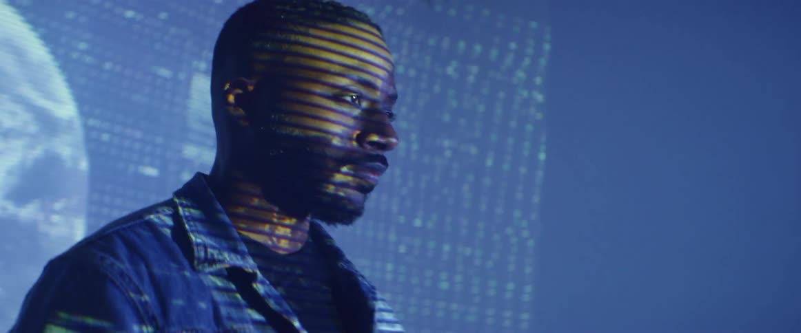A man poses in front of a wall projected with a digital image of a spinning planet