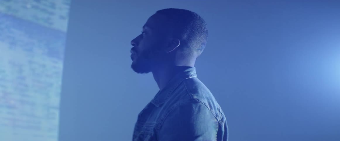 A man stands in the dark room watching a projector image