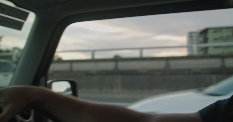 Highway traffic passes by a man who checks his watch while driving