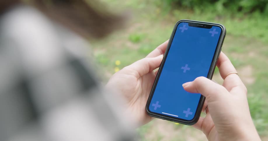 A woman scrolling on a smartphone outside